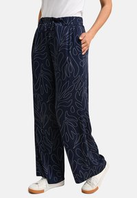 Navy wide-leg pants with a white leaf pattern, featuring an elastic waistband and side pockets, made from lightweight fabric.