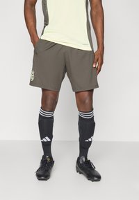 Mørkegrå atletikshorts med logo, parret med sorte knæhøje sokker med hvide striber. Sorte fodboldstøvler med snørebånd.