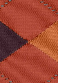 Gros plan sur un tissu tricoté avec un motif géométrique en diamants de couleur orange, violet et jaune, avec de petites accents de points turquoise.