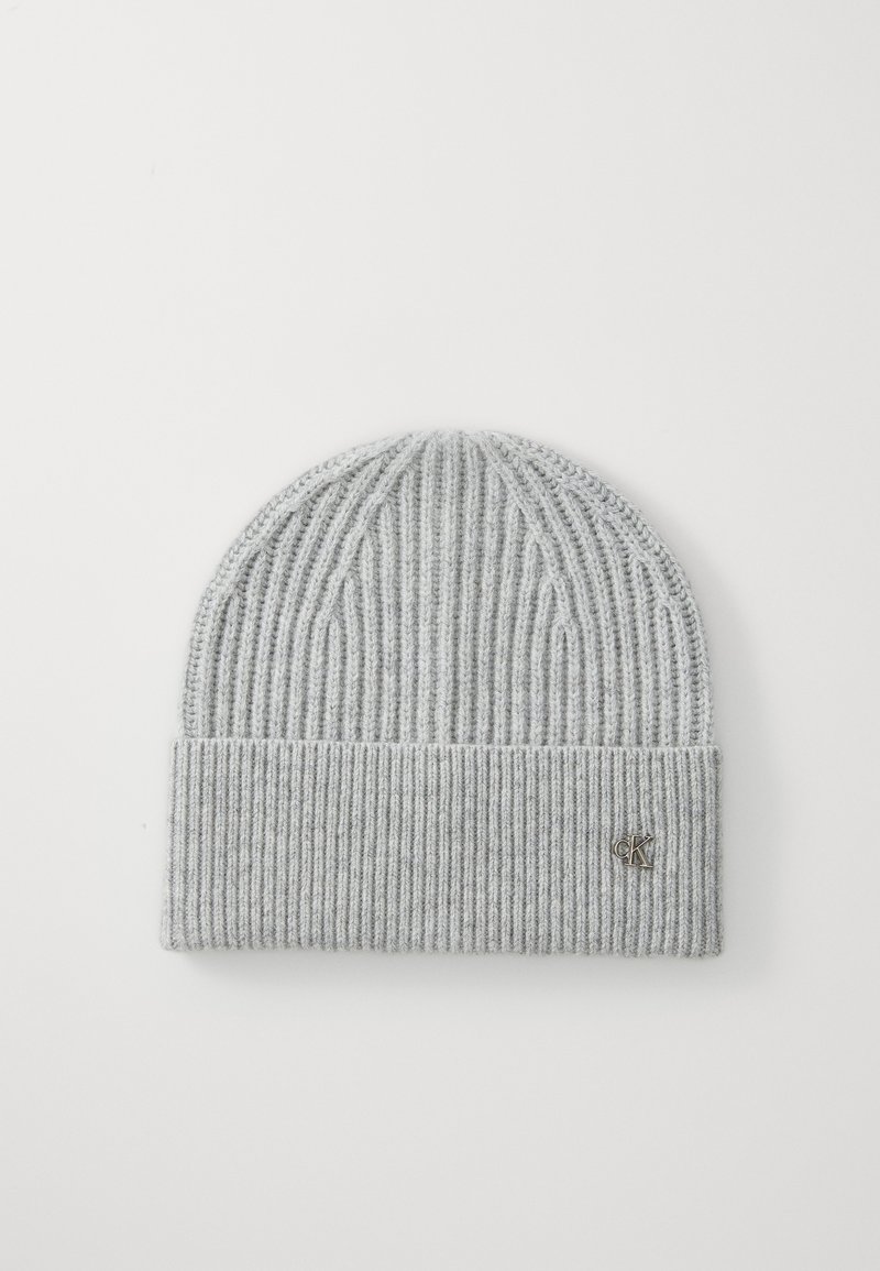 Bonnet en tricot gris avec un motif de côtes verticales et un revers replié. Présente un petit accent logo en argent sur le revers. Texture douce.