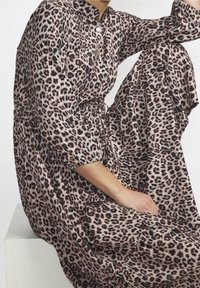 Lepardmönstrad klänning i mjukt tyg med krage och trekvartslånga ärmar. Har ett elastiskt midjeband och en flödande kjol.