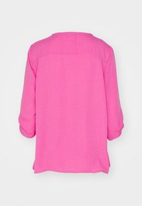 Rosa Bluse mit lockerer Passform, dreiviertelärmlig und texturierter Oberfläche. Verfügt über einen runden Ausschnitt und einen geraden Saum.