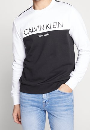 Sweatshirt noir et blanc à col ras du cou comportant le logo "Calvin Klein New York" sur la poitrine, fabriqué en tissu mélangé en coton.