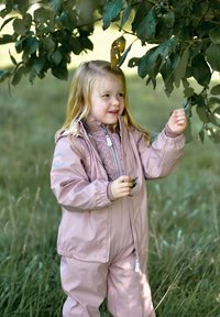 Roza nepremočljiva jakna z elastičnimi manšetami in zadrgo, v kombinaciji z ujemajočimi hlačami. Otrok nabira liste pod drevesom na travnati površini.