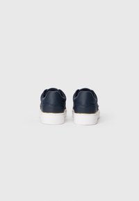 Tengerészkék bőr sneaker cipők fehér talppal, arany díszítéssel a szegélyen, kerek orr kialakítással és párnázott gallérral a kényelem érdekében.
