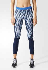 Blaue und marineblaue Leggings mit Muster aus einem dehnbaren Material, ausgestattet mit einem breiten Bund und kontrastierenden einfarbigen Einsätzen an den Seiten.