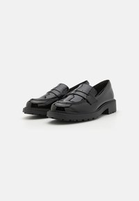 Schwarze Lackleder-Loafers mit derben Gummisohlen, versehen mit einem dekorativen Riemen und subtilen Ziernähten auf dem Obermaterial.