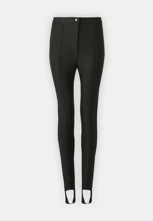 Leggings negros hechos de material elástico, con un diseño ajustado, cierre frontal con botones y cortes en los tobillos para facilitar el movimiento.