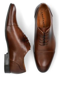 Brązowe skórzane buty eleganckie z okrągłym noskiem, minimalnym sznurowaniem i gładką teksturą. Posiadają przeszywane akcenty i niski obcas.