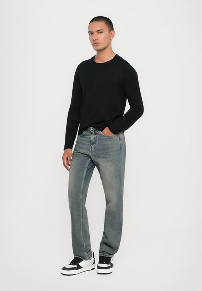 Black long-sleeve sweater, light blue denim jeans, black and white sneakers. Simple design, fitted shape, standard textures and finishes.