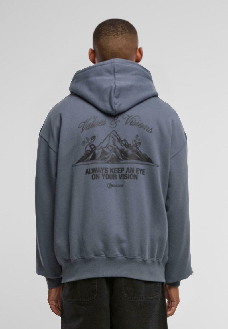 Grijze hoodie met een grote achterkantafbeelding van bergen en tekst. Losse pasvorm met ribgebreide manchetten en rand. Zachte textuur.