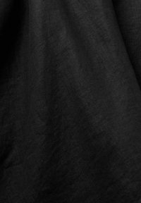 Tela de lino negro con una superficie texturizada, que presenta sutiles variaciones en tono y un caído suave y natural. Adecuada para diversas aplicaciones textiles.