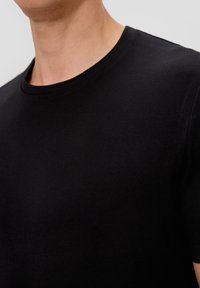 T-shirt noir à col ras du cou fabriqué en tissu doux, avec une coupe slim et des manches courtes, présentant une texture lisse et sans motifs visibles.