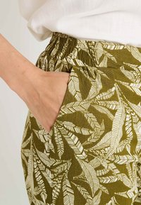 Pantalons à taille élastique en vert olive avec des motifs de feuilles blanches ; dotés de poches latérales et d'un tissu texturé pour le confort.