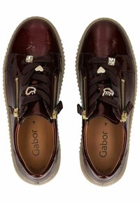 Zapatillas de charol burdeos con acabado texturizado, cremalleras laterales, acentos de hardware decorativos y una suela beige acolchada. Marca Gabor en el interior.