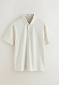 Krēmkrāsas īsroku polo krekls ar apkakli un vienu pogu plāksnītē, attēlots uz vienkārša gaiša fona.