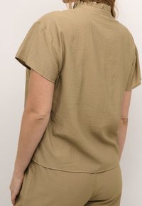 Top khaki a maniche corte con tessuto testurizzato, caratterizzato da un colletto arricciato e una vestibilità rilassata, visto da dietro.