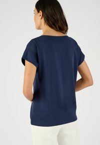 Camiseta de manga corta azul marino con un escote amplio, ajuste relajado y material de algodón suave. Detalles de costura a lo largo de los hombros.