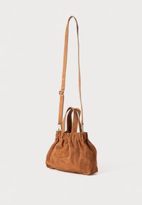 Bruine suède handtas met een gathered top, dubbele korte handvatten en een lange verstelbare schouderband. Zachte textuur, compacte vorm en minimalistisch ontwerp.