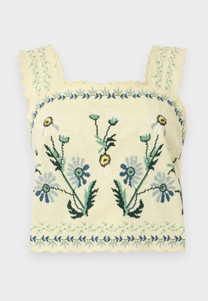 Kollane lühendatud tanktop sinise ja rohelise lillelise tikandi ning servade lainelise äärega rihmadel ja äärel.