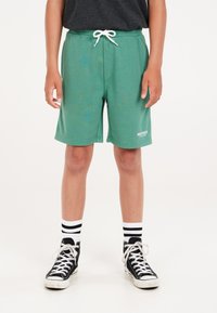 Groene trainingsshorts van katoen met een elastische tailleband en witte trekkoord, voorzien van een logo in het wit aan de onderste linkerkant.
