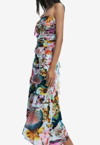 Robe sans bretelles à fleurs avec un corsage ajusté et des détails froncés. Fabriquée en tissu léger et coloré, offrant une silhouette fluide.