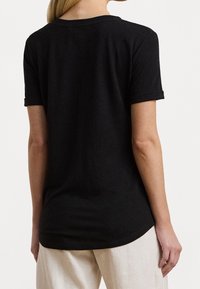 Svart bomulls t-shirt med rund halsringning, korta ärmar och en lätt rundad kant. Slät textur, enkel design utan mönster eller detaljer.