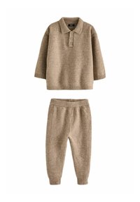 Pull en maille beige avec col polo et trois boutons, associé à un pantalon tapered assorti avec taille élastique et poignets côtelés.