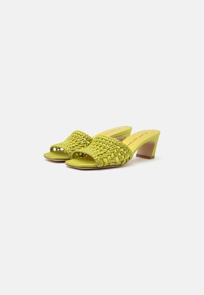Paire de mules tissées jaune-vert à bout ouvert avec talons blocs sur fond blanc.