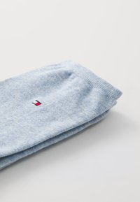 Calcetines de algodón de color azul claro con una textura suave, que presentan un pequeño logotipo en rojo, blanco y azul. Doblegados de manera ordenada sobre un fondo blanco.