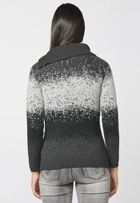 Pull en tricot avec un motif dégradé allant du noir au gris, doté d'un col montant côtelé et de manches longues. Texture douce avec une coupe ajustée.