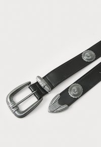 Cinturón de cuero negro con una hebilla de tono plateado que presenta un diseño texturizado, adornado con dos acentos metálicos decorativos a lo largo de la correa.