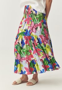 Falda maxi floral con un diseño vibrante de flores rosas, azules y verdes sobre un fondo claro, terminada con un dobladillo con volantes.