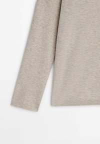 Pull beige à manches longues, fabriqué en tissu doux et texturé. Présente un ourlet et des poignets côtelés, avec un design simple et uni.