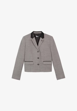 Blazer court à motif à carreaux noir et blanc, avec un col en cuir noir, deux poches avant et trois boutons sur le devant.