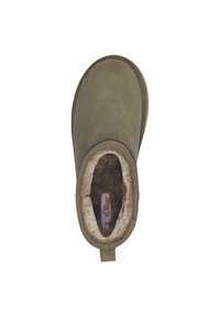 Zapato tipo slip-on de color verde oliva con suave forro de piel sintética, exterior de ante texturizado, costuras prominentes y una tira de tela en el talón.