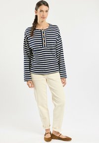 Navy and white striped long-sleeve top with four wooden buttons, paired with beige corduroy pants and brown suede flats.