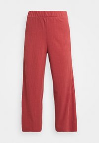 Pantalons tricotés côtelés rouge rouillé avec taille élastique et jambes droites sur un fond blanc uni.