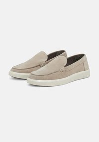 Beige suede slip-on shoes with a rounded toe, soft texture, white rubber sole, and decorative stitching detail on the upper.