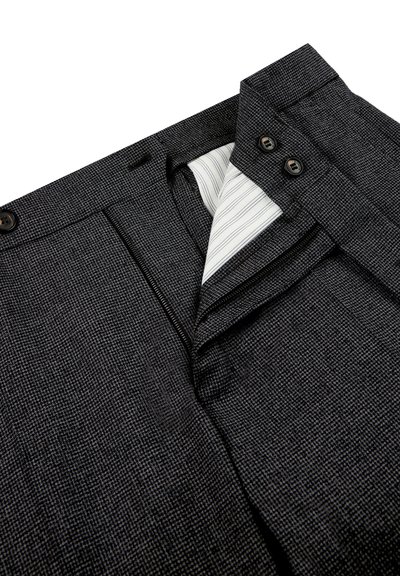 Schwarz gemusterte Hose mit Reißverschluss und zwei Knöpfen, innen mit einem weißen und blauen gestreiften Futter. Texturierte Stoffdetails sichtbar.