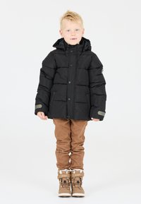 Giacca a spirale nera con cappuccio, bottoni a scatto e accenti grigi. Pantaloni in corduroy marroni e stivaletti invernali beige con foderina in pelliccia e cinturini.