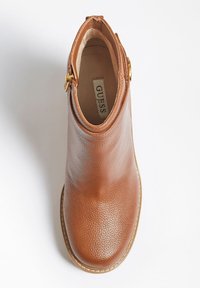 Hnědá kožená kotníková bota s texturovaným povrchem, zaoblenou špičkou, šitými detaily a zlatým kovovým prvkem na kotníku. Viditelná vnitřní etiketa.