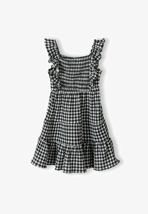 Haljina od crno-bijelog ginghama s volanima na naramenicama, naboranom tijelu i slojevitom, raširenom rubu. Tkanina ima laganu teksturu.