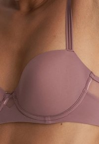 Mauve-bh med släta, formade kupor och smala justerbara band; har en sömlös design och delikata sömnadsdetaljer.