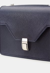 Borsa a tracolla blu navy in sintetico con finitura testurizzata, patta angolare, chiusura in tono argento e cuciture a contrasto lungo i bordi.