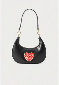 Black crescent-shaped handbag with gold zipper, heart-shaped gold and red emblem reading "Love Moschino," and gold heart-shaped strap links.
