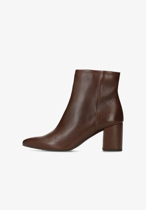 Botte basse en cuir marron avec un bout pointu, une texture lisse et un talon épais. Elle présente un design minimaliste et une couture latérale sans coutures.