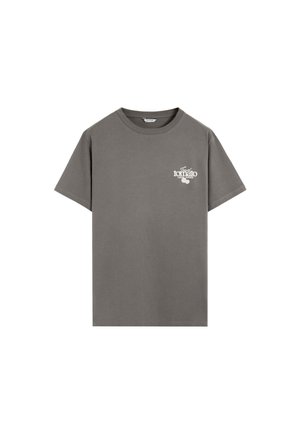 Camiseta gris de manga corta con cuello redondo con texto blanco pequeño "Jugos locales de tomate fresco" y gráfico de tomate en el pecho izquierdo.