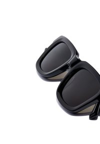 Mustad ümarad ruudukujulised prillid paksude läikivate raamidega ja tumedate toonitud läätsedega valgel taustal.