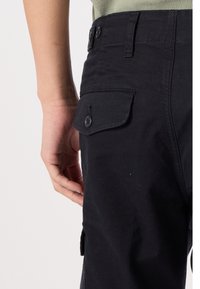 Czarne spodnie bojówki z boczną kieszenią, dwoma guzikami na pasku oraz gładką fakturą. Tylna kieszeń posiada klapkę i zapięcie na guzik.